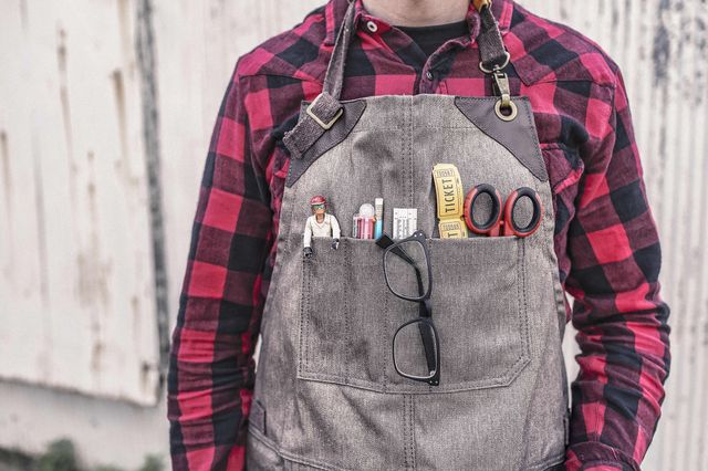 Person's dungarees chest pockets filled with strange mix of items - a play figure, pens, ruler, scissors, glasses and tickets.